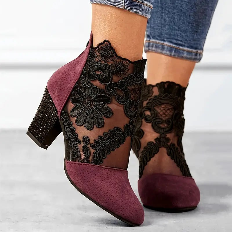 Mauve high-heeled shoes with black lace detailing worn by a person.