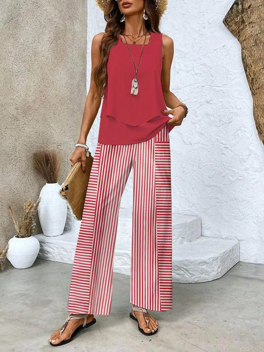  Woman wearing a layered sleeveless blouse paired with loose-fitting pants against a plain background.