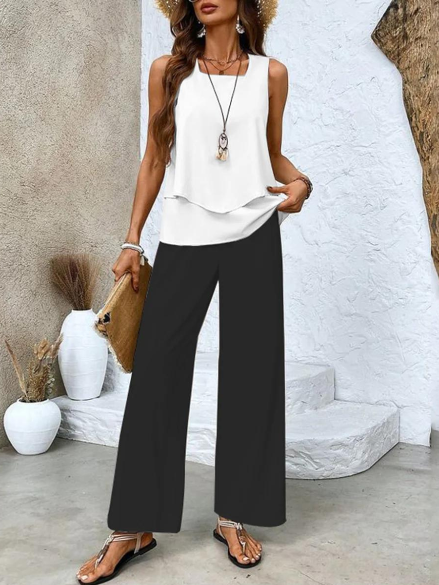  Woman posing in a coordinated sleeveless outfit with flowing pants on a plain background.