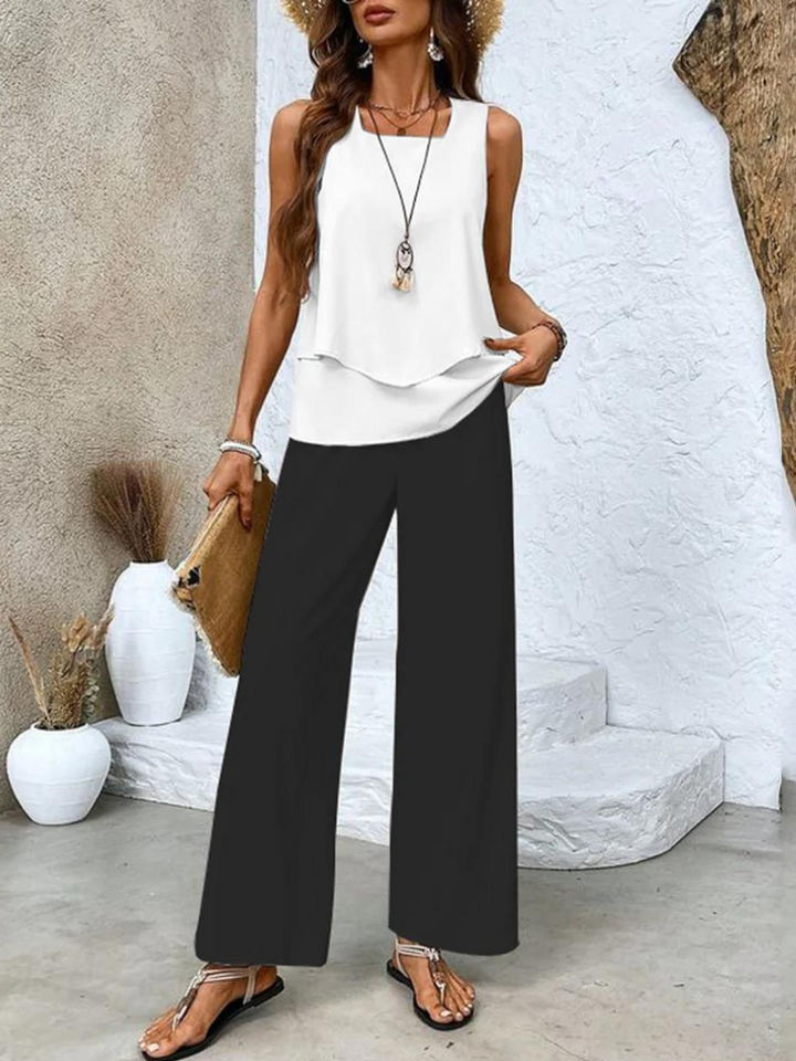  Woman posing in a coordinated sleeveless outfit with flowing pants on a plain background.
