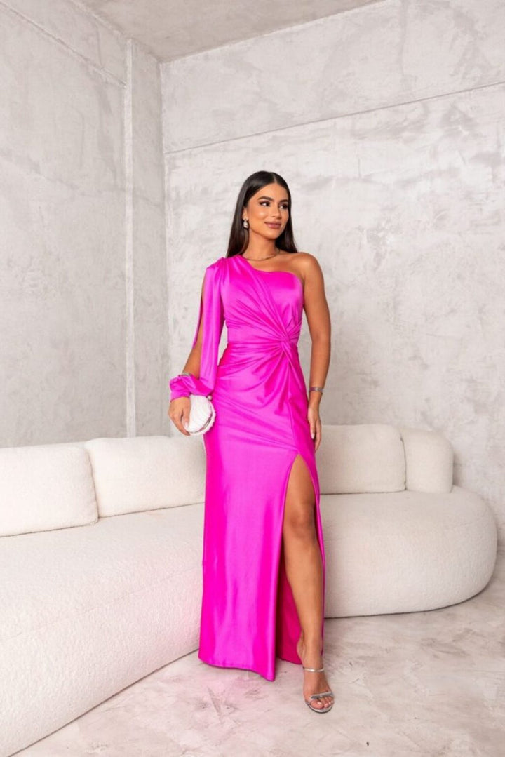 Woman wearing an asymmetrical evening gown with a flowing skirt on a plain background.