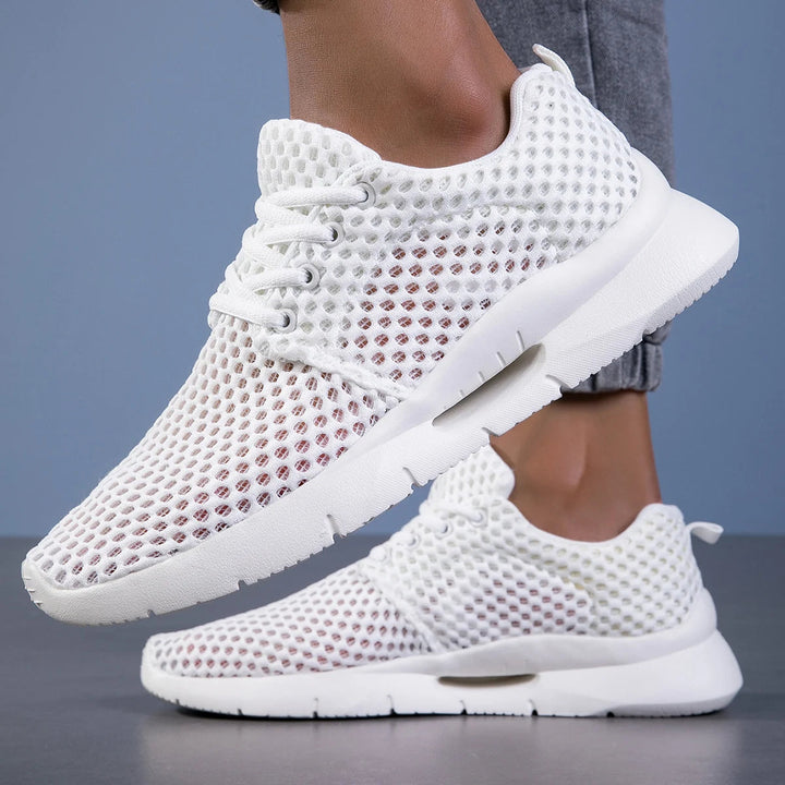 White mesh sneakers side angle on gray floor