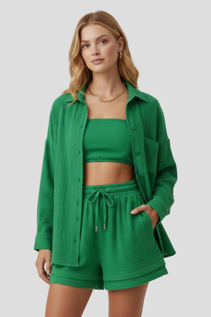 Female model showing loose green blouse fit and shorts on plain gray background.