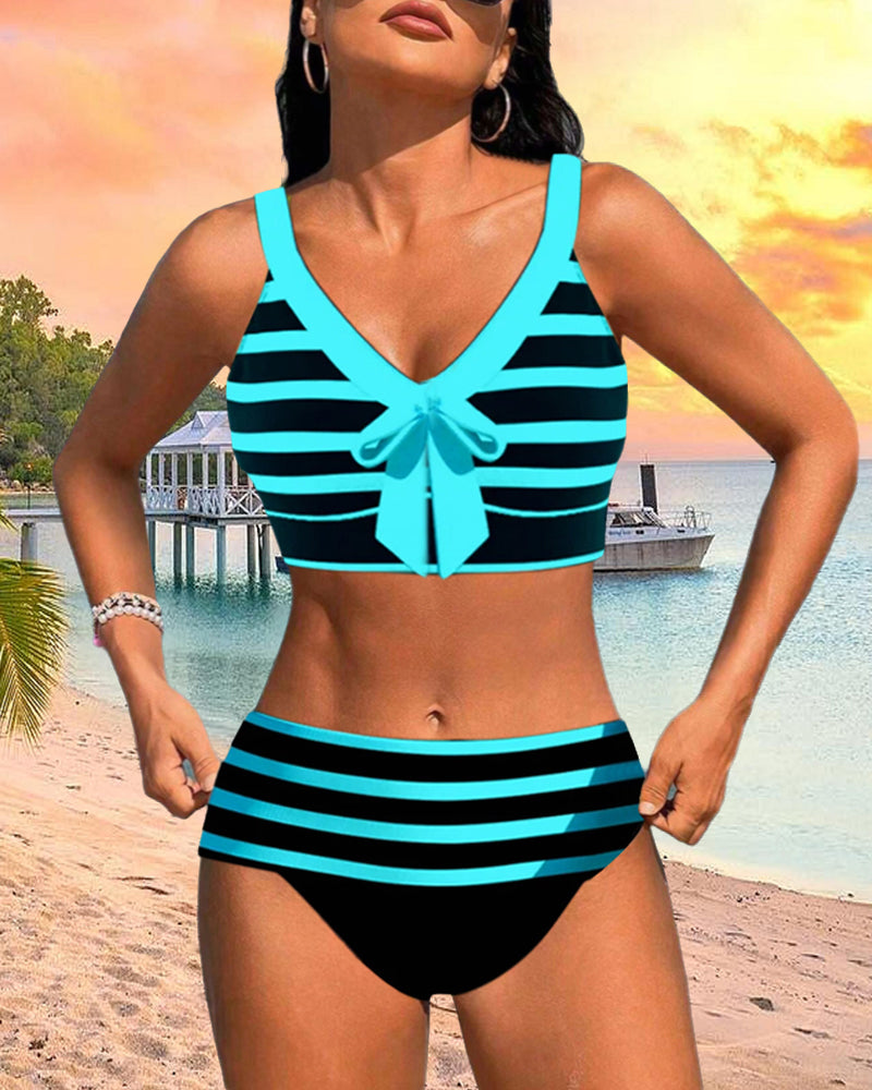 Female model in bright striped bikini with a sunny beach background.