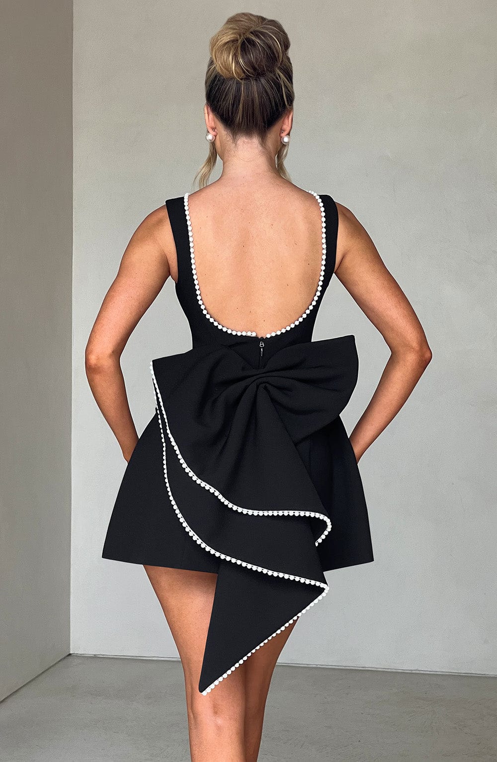 Female model displaying a tailored occasion dress with a modern mini length.