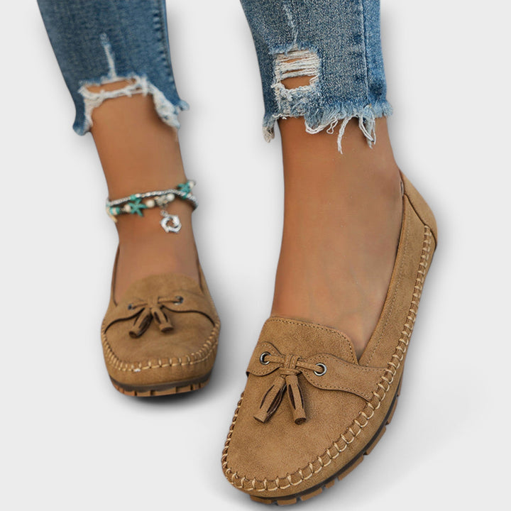 Brown loafers worn with ripped jeans on a white background