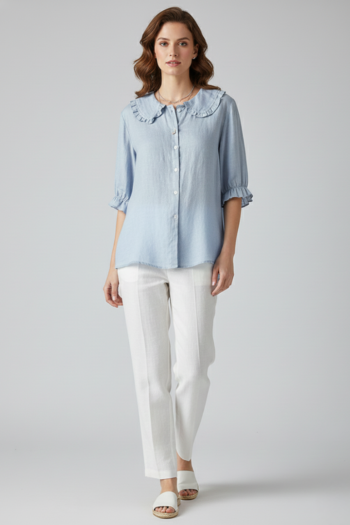 Blue blouse with ruffled neckline on light grey background