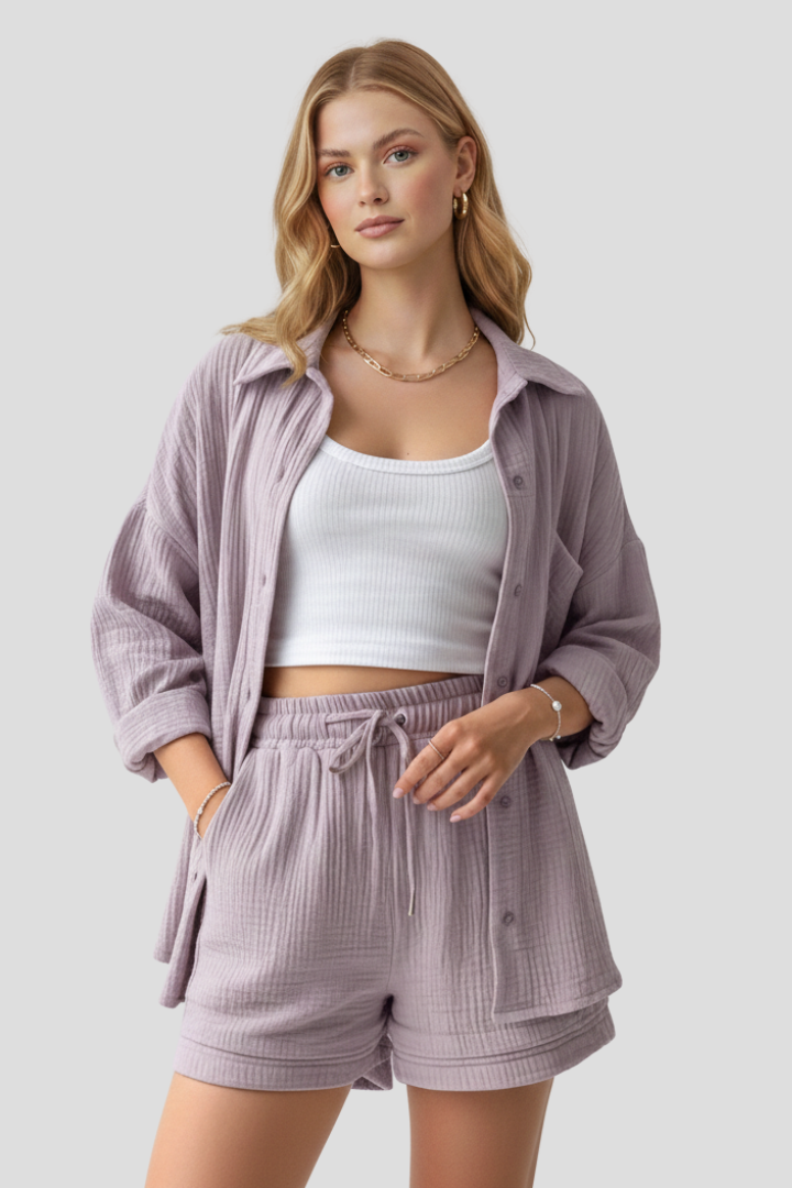 Woman standing in matching blouse and shorts, plain gray background.