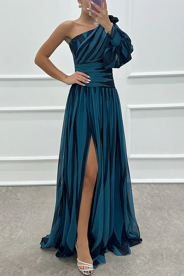 Female model in a flowing striped dress with a front slit on a plain background.