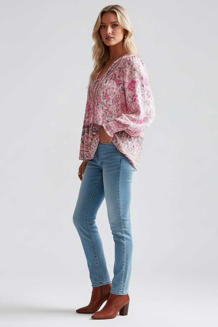 Soft pink boho top paired with blue jeans and ankle boots with heels in gray background