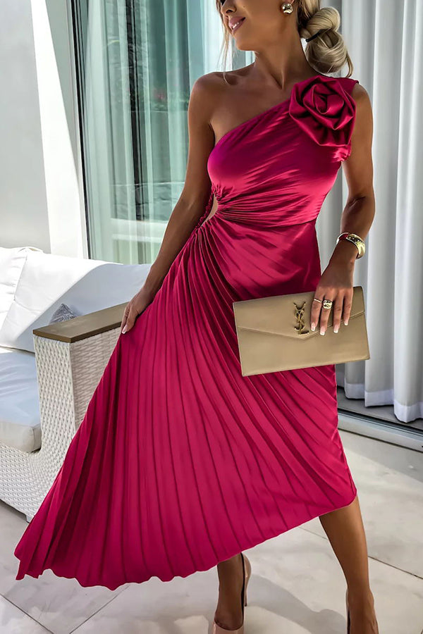 Woman model wearing a one shoulder midi dress with pleated skirt and rose shoulder detail on a plain background.