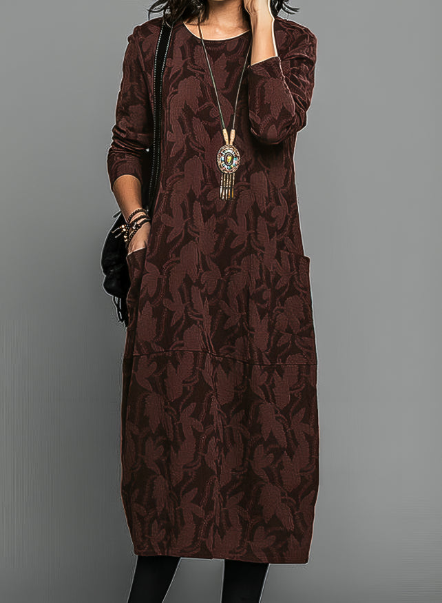 Female model posing in printed midi dress on gray background.