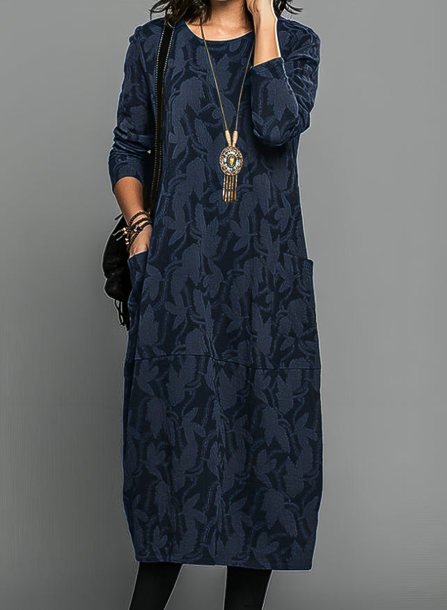 Woman showing full length printed dress with elegant fit, gray background.