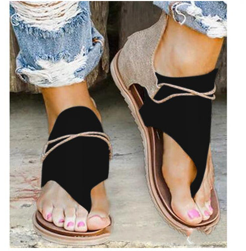 Foot wearing sandals in natural stance on plain background.