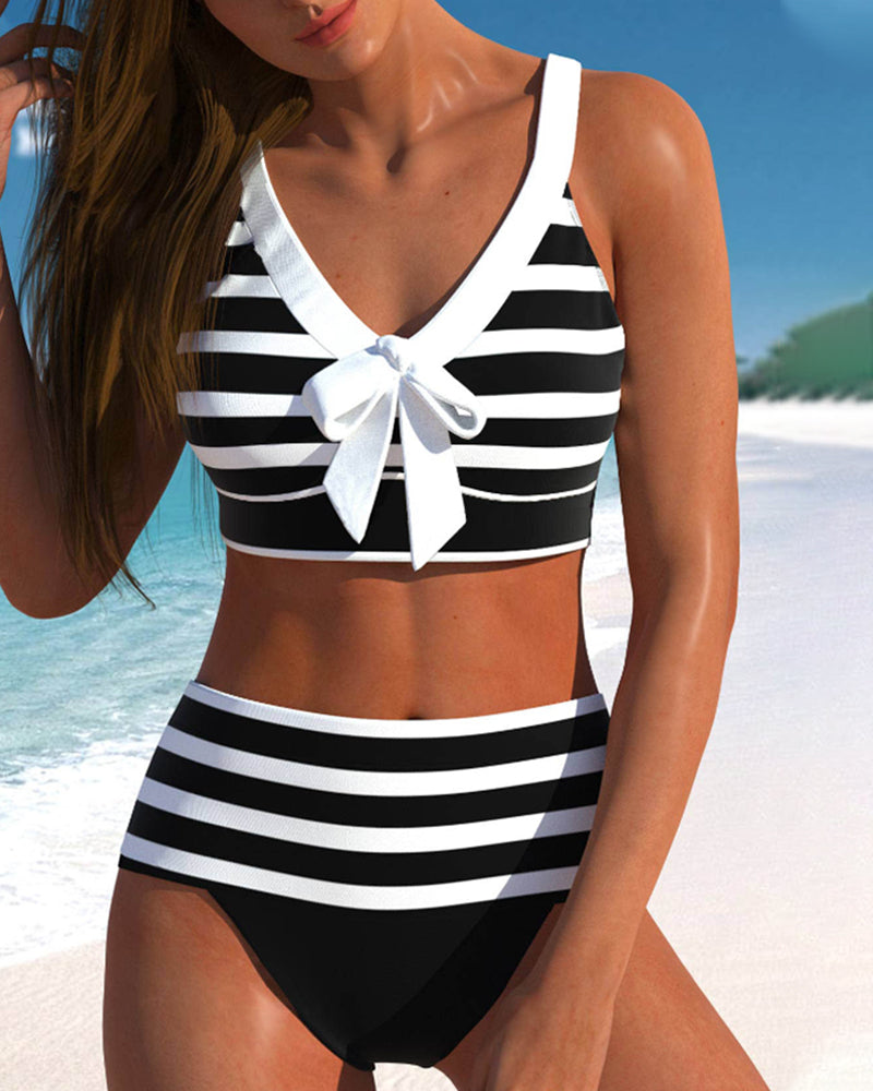 Female model wearing a striped high-waist bikini on a beach background.