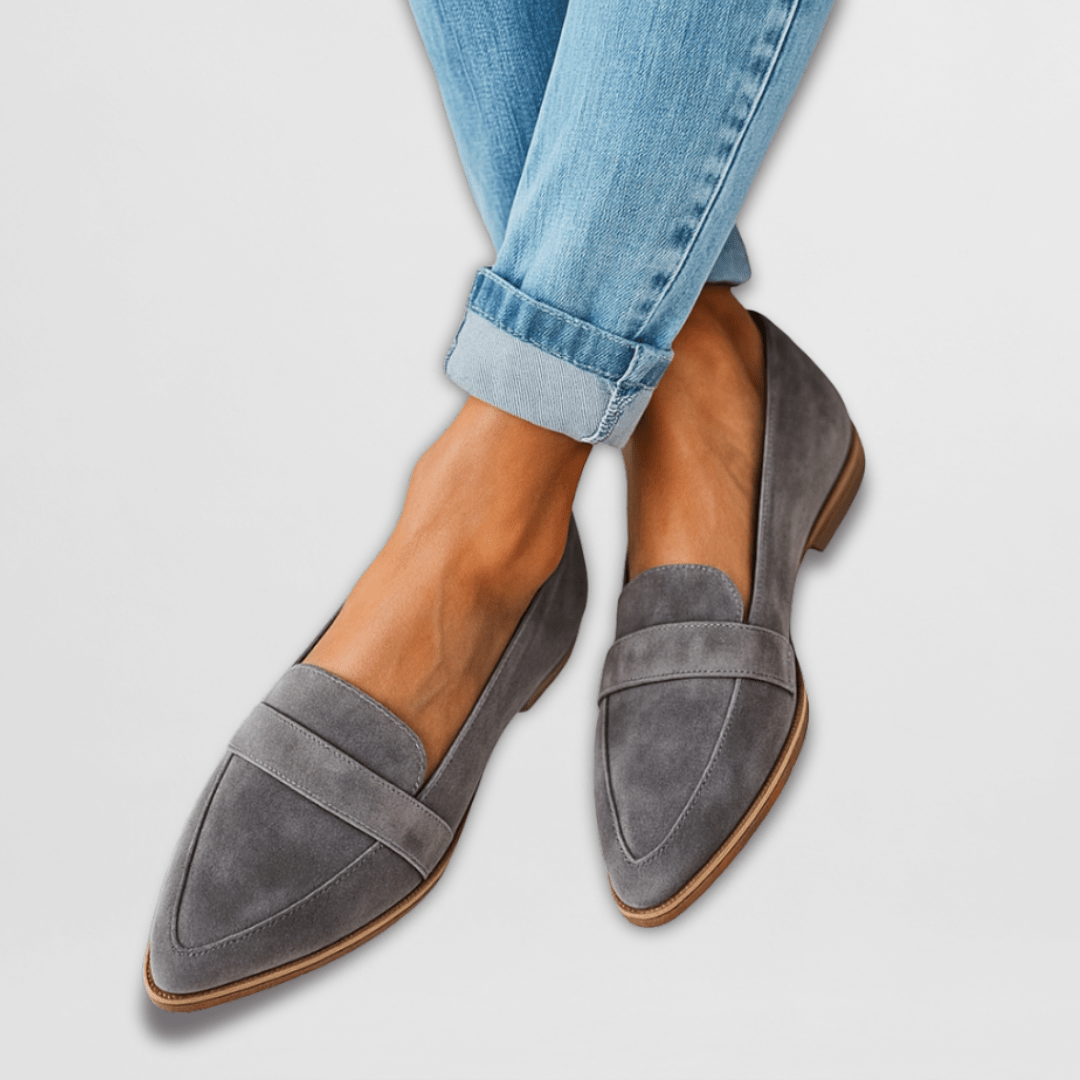  Woman showcasing closed-toe loafers on a plain background.