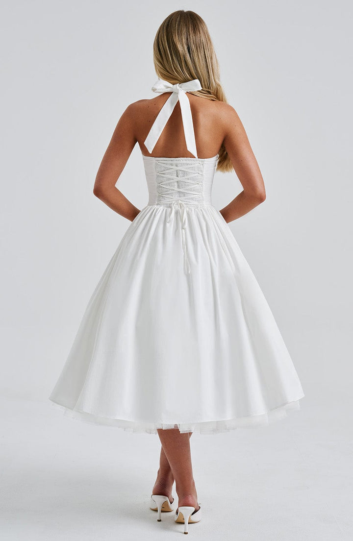 Female model in chic occasion dress against gray plain backdrop, back view