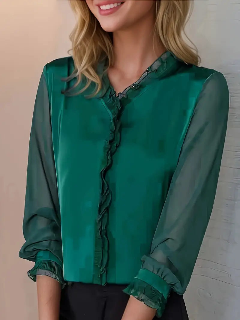 Woman wearing an elegant long sleeve ruffle blouse on a plain background.