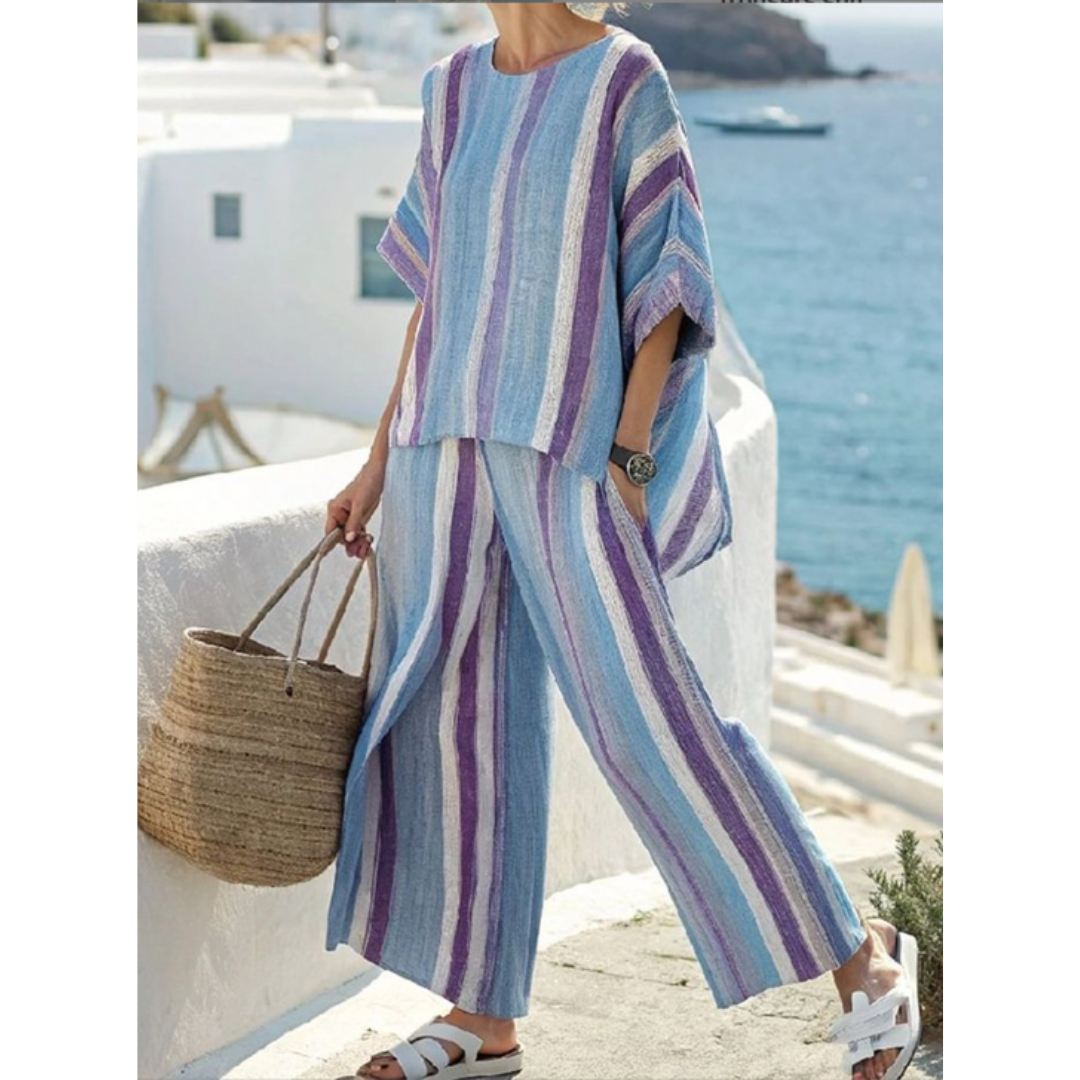Woman wearing a striped two-piece skirt set on a beach background.