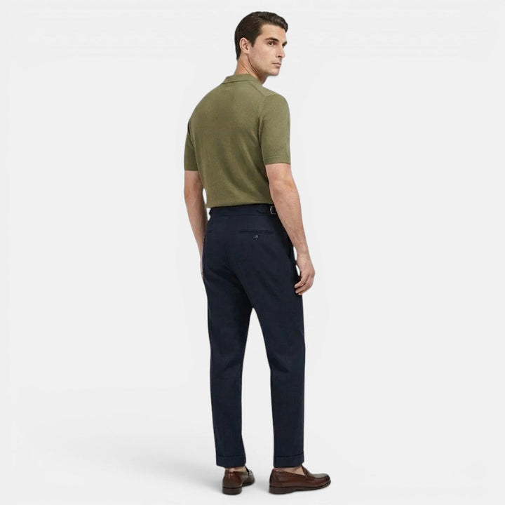 Female model showcasing classic trousers with front pleat accents on a plain background.