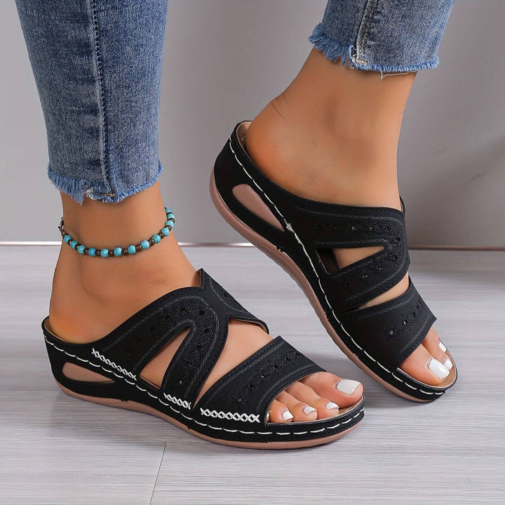  Female model showing open-toe sandals on a plain background.