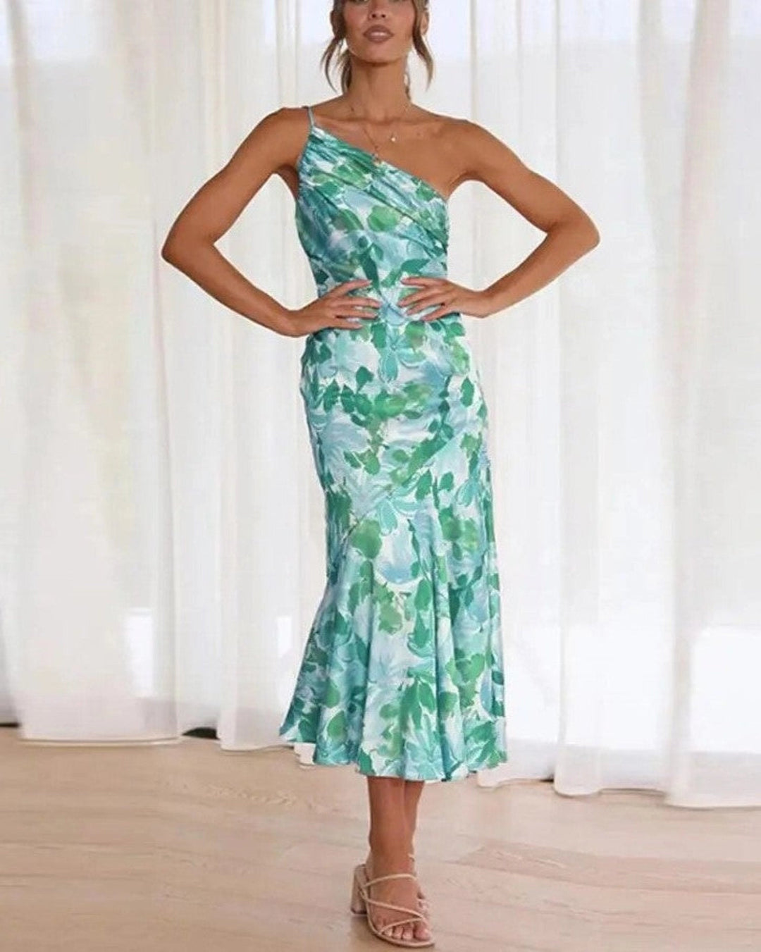 Woman standing in elegant floral attire with visible feet against a plain background.