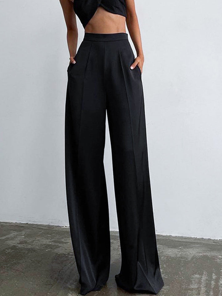 Female model wearing long satin pants against a plain background.