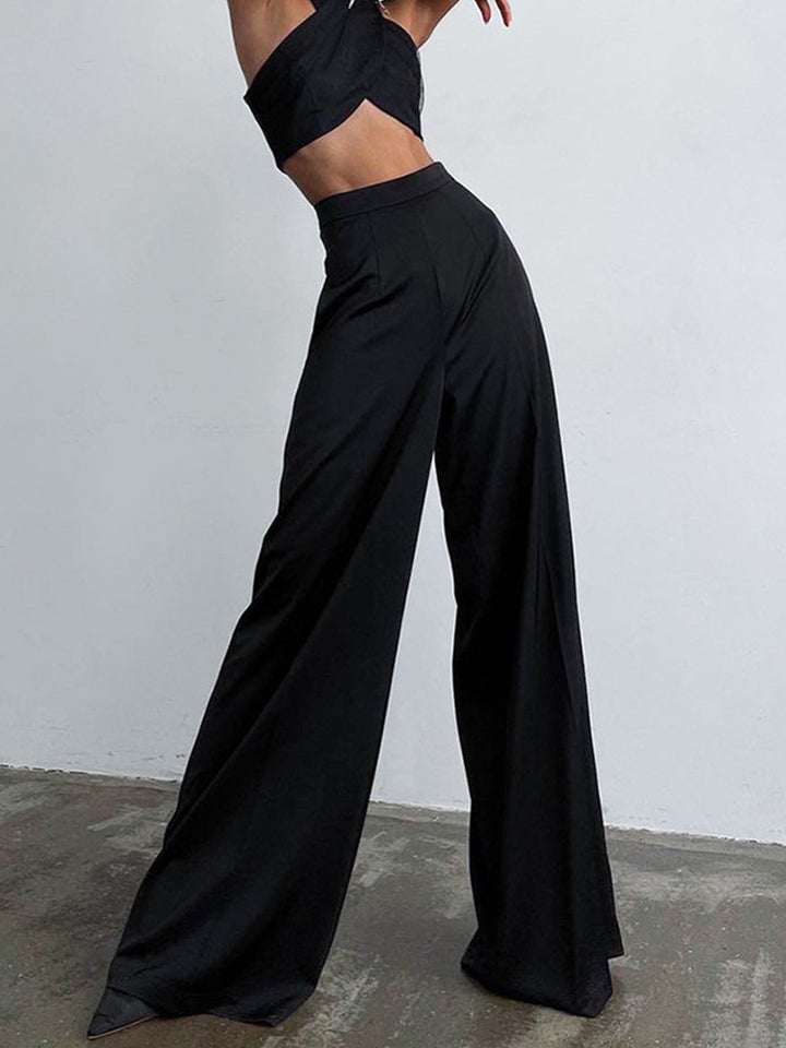 Woman wearing sleek long pants against a simple plain background.