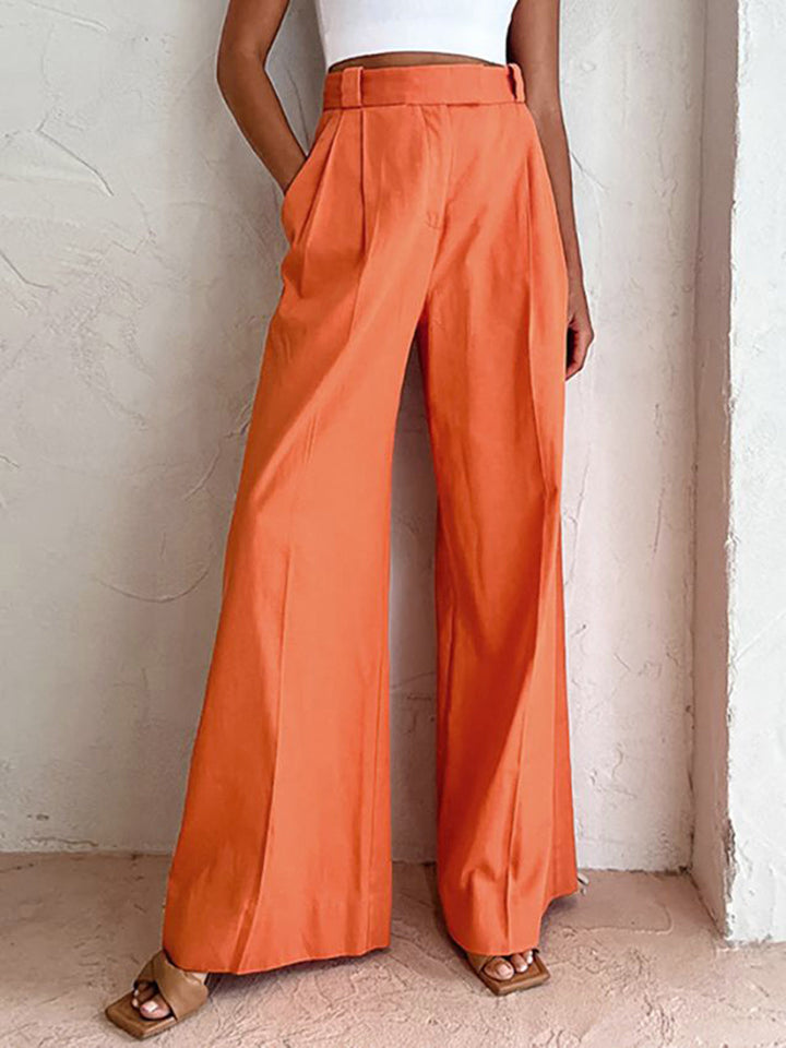 Woman wearing long mid waist shift pants against a plain background.