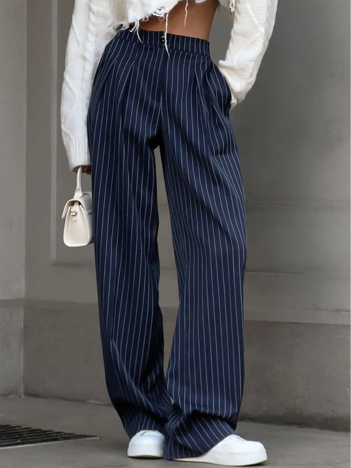 Woman wearing long regular fit pants on a plain background.