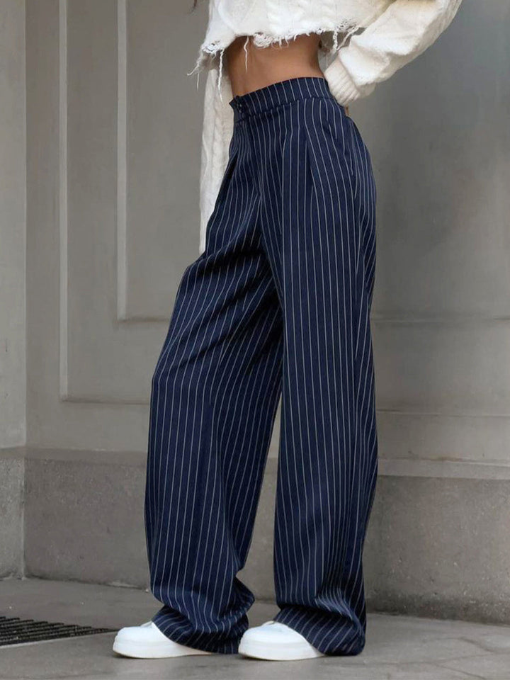 Female model styling long pants with a clean everyday look on a plain background.