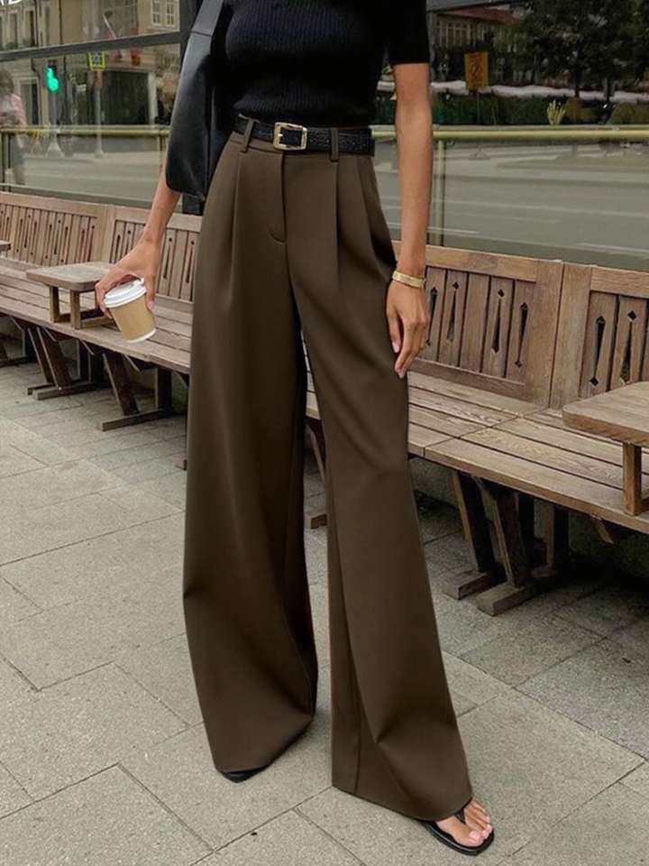 Woman styling woven fabric pants for casual outfits on a plain background.
