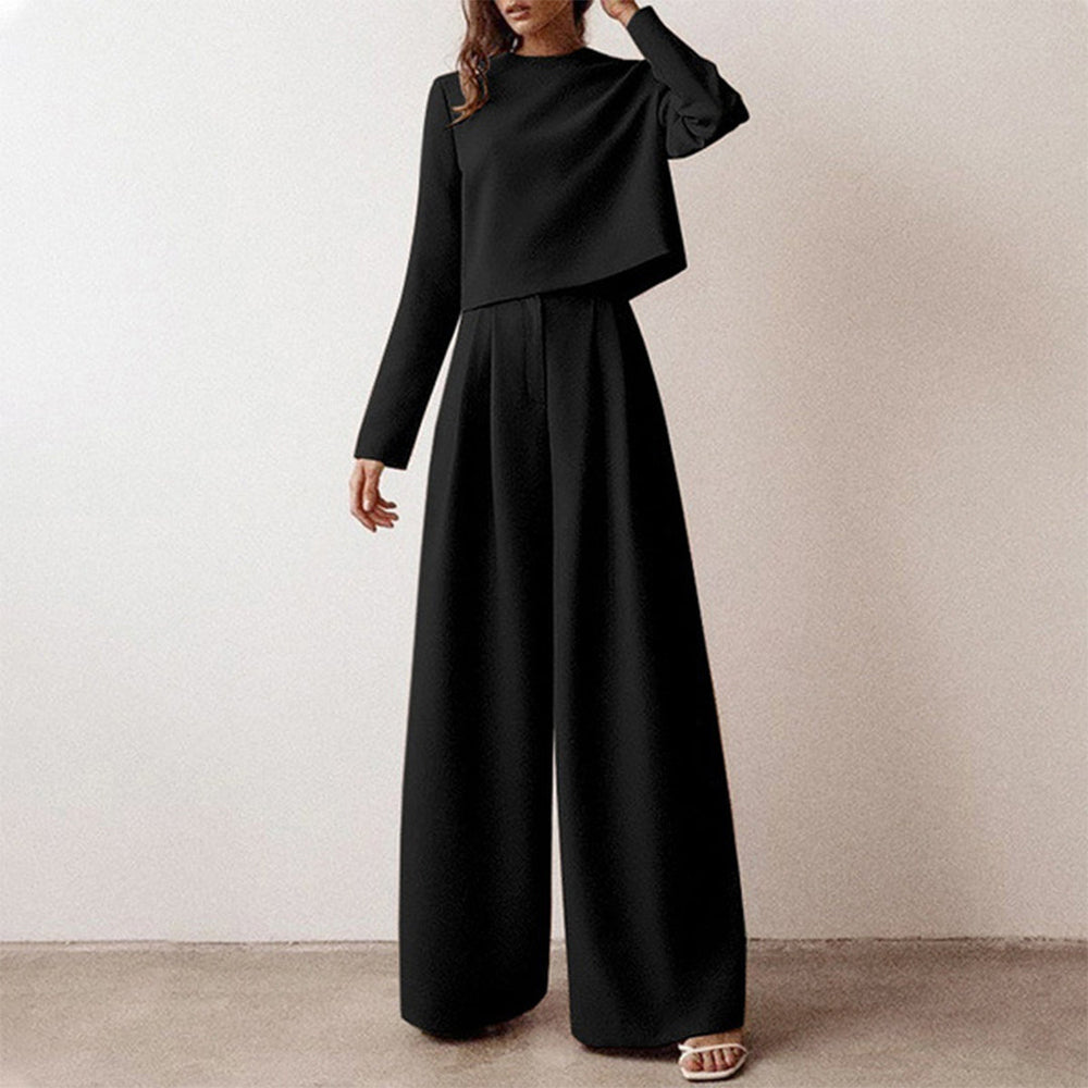 Woman showcasing a coordinated two-piece outfit with a cropped top and flowing pants on a plain background.