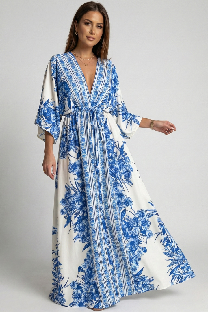 Woman wearing blue patterned maxi dress on plain gray background.