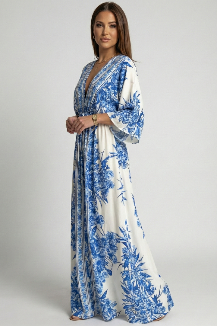 Woman posing in V-neck resort dress on plain gray background.