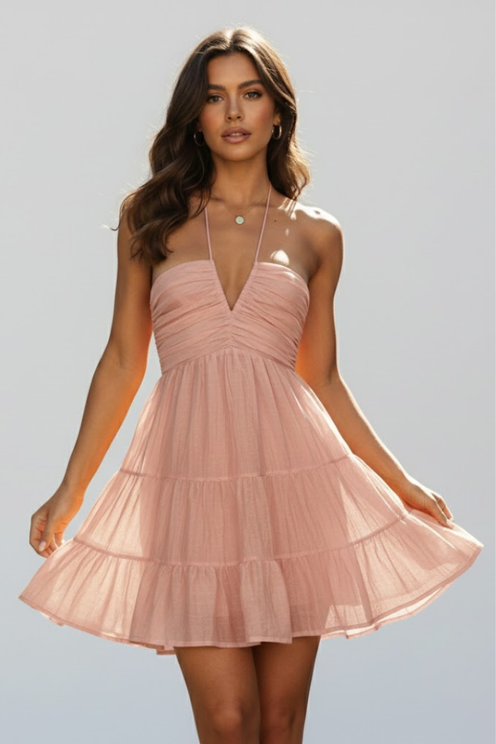 Model wearing pink mini dress posing front view against in gray studio background