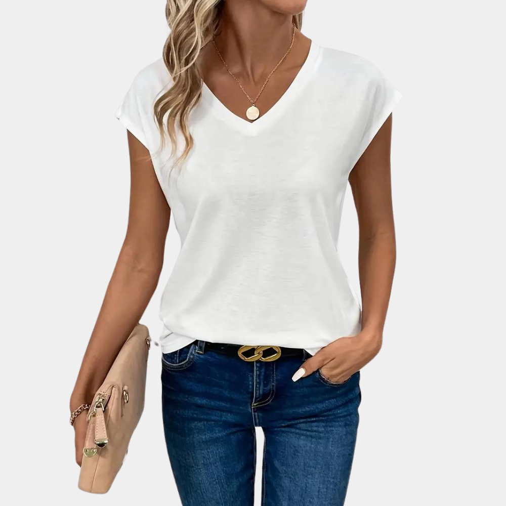 Female model posing in relaxed short sleeve top, plain background.