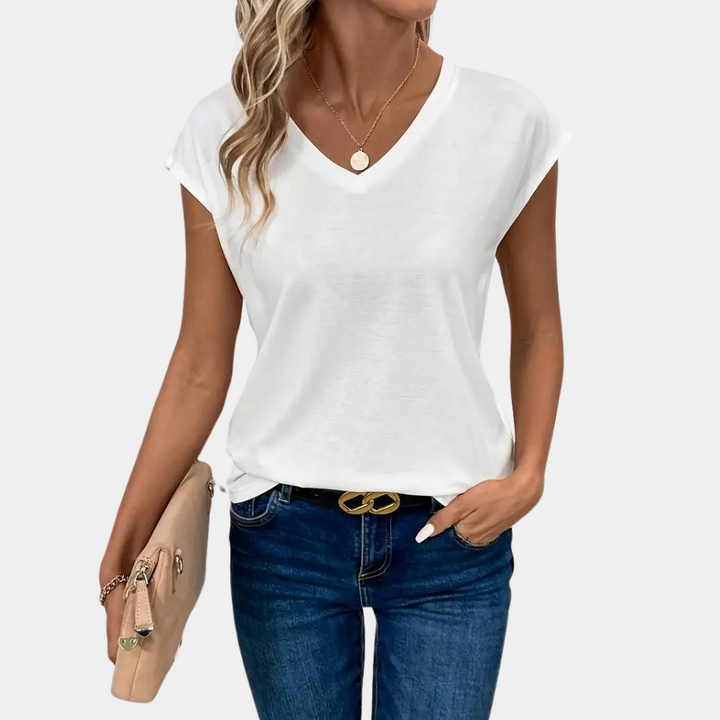 Female model posing in relaxed short sleeve top, plain background.