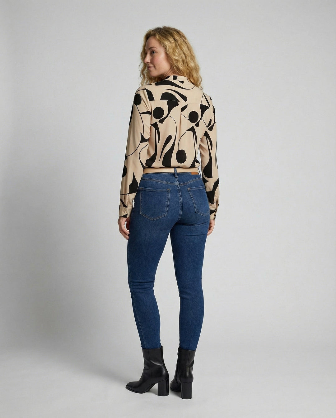 Female model in a stylish blouse paired with a clean and simple backdrop.