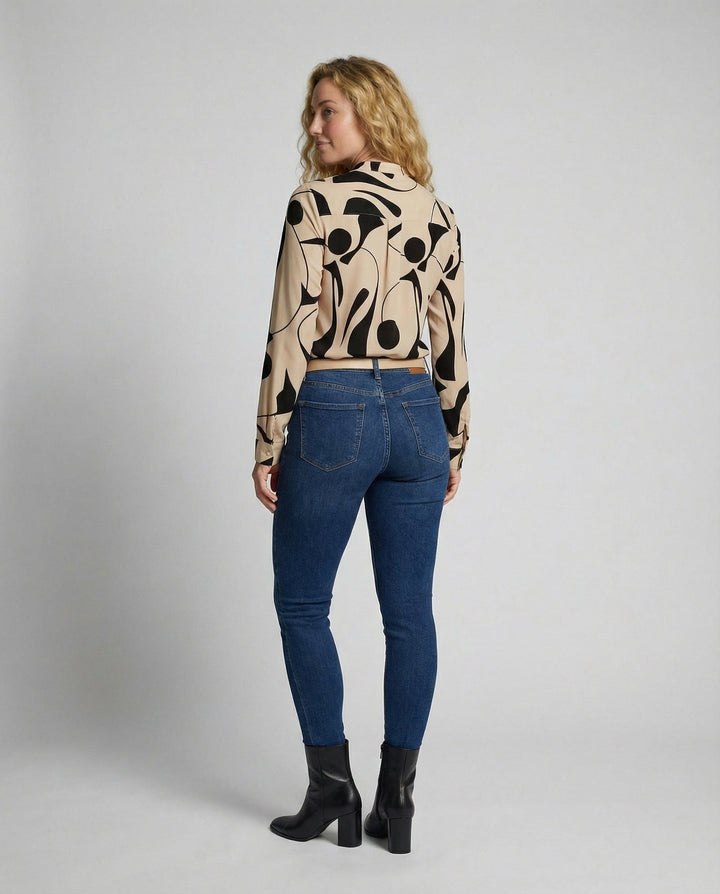 Female model in a stylish blouse paired with a clean and simple backdrop.