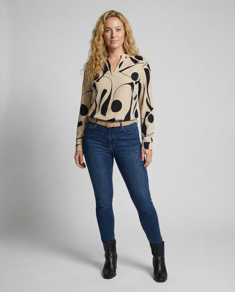 Woman showcasing a classic long-sleeve blouse on a plain background.