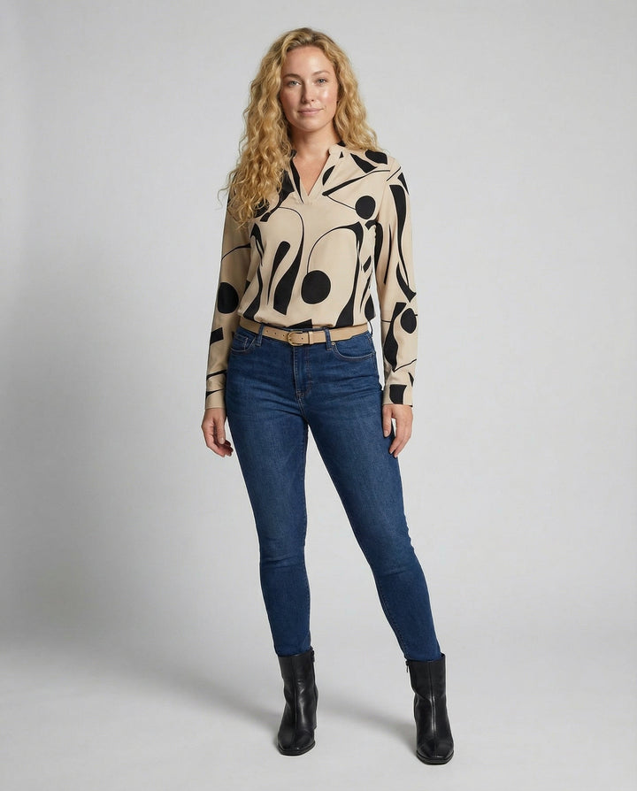 Woman showcasing a classic long-sleeve blouse on a plain background.