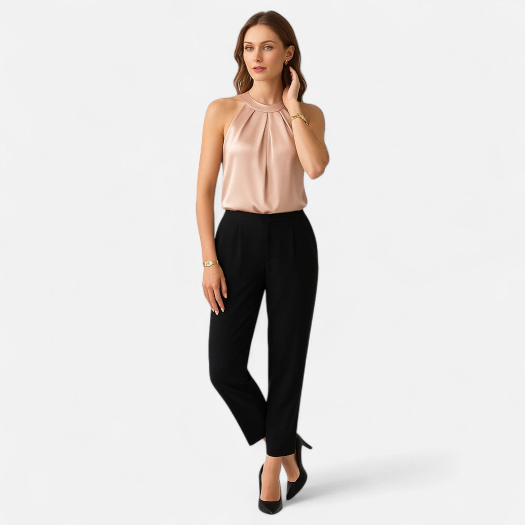 Female model showcasing a pleated satin sleeveless blouse against a plain background, full length