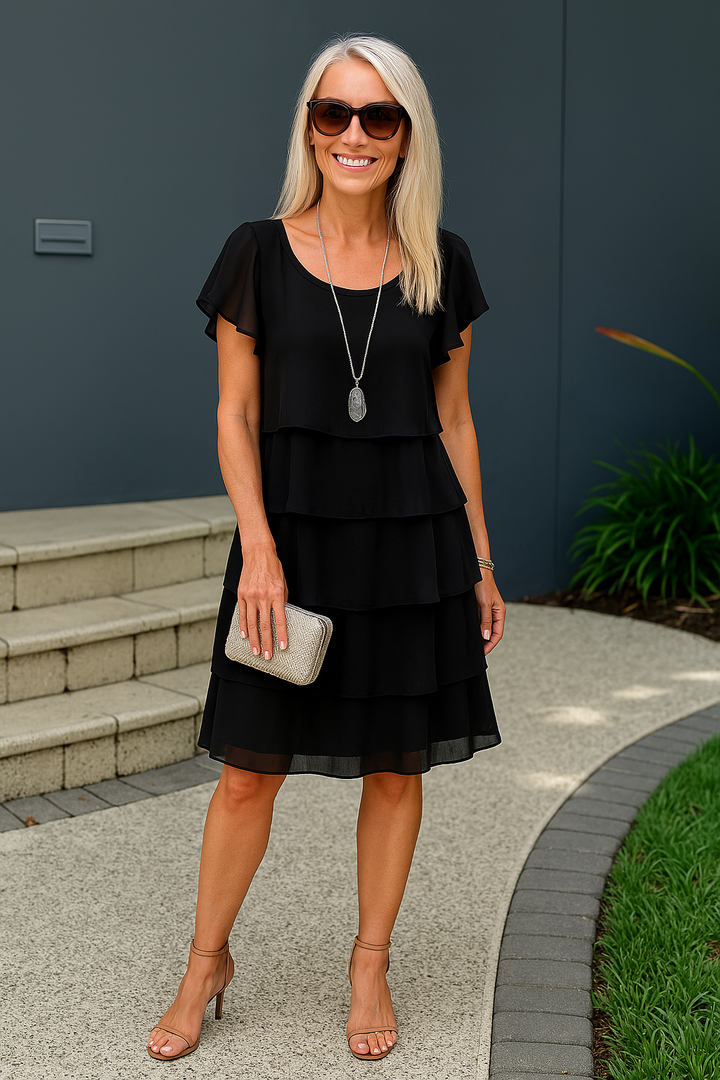  Model in a refined layered midi dress styled for everyday wear on a plain background.