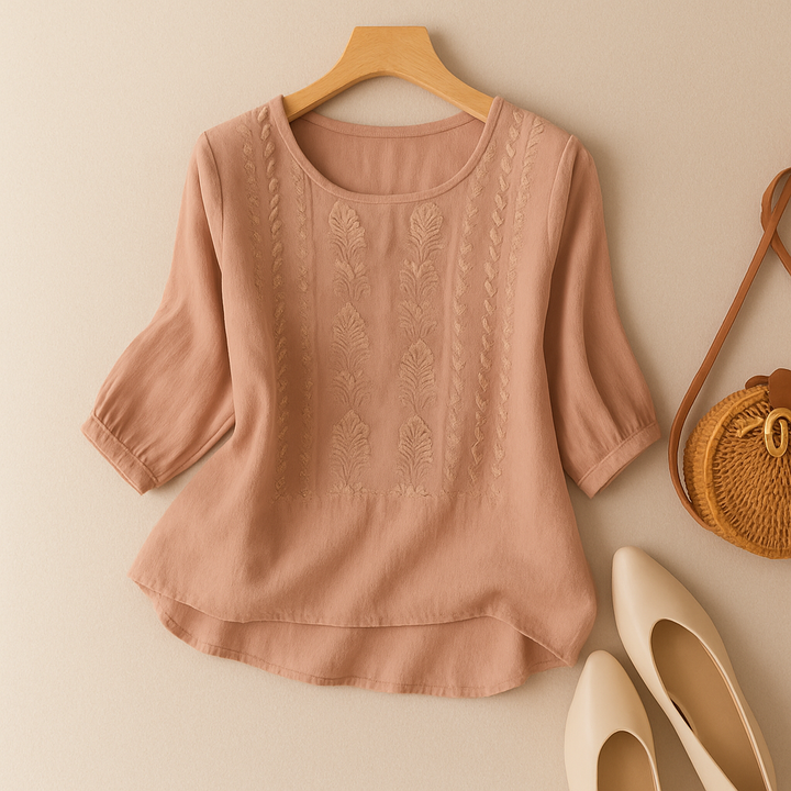 Summer embroidered blouse styled on a model with plain backdrop.