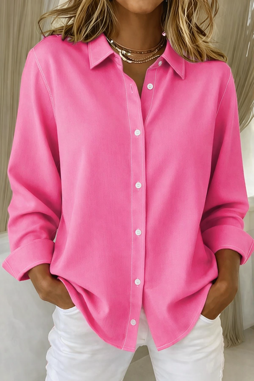 Female wearing a collared blouse with a button-front design against a plain background.