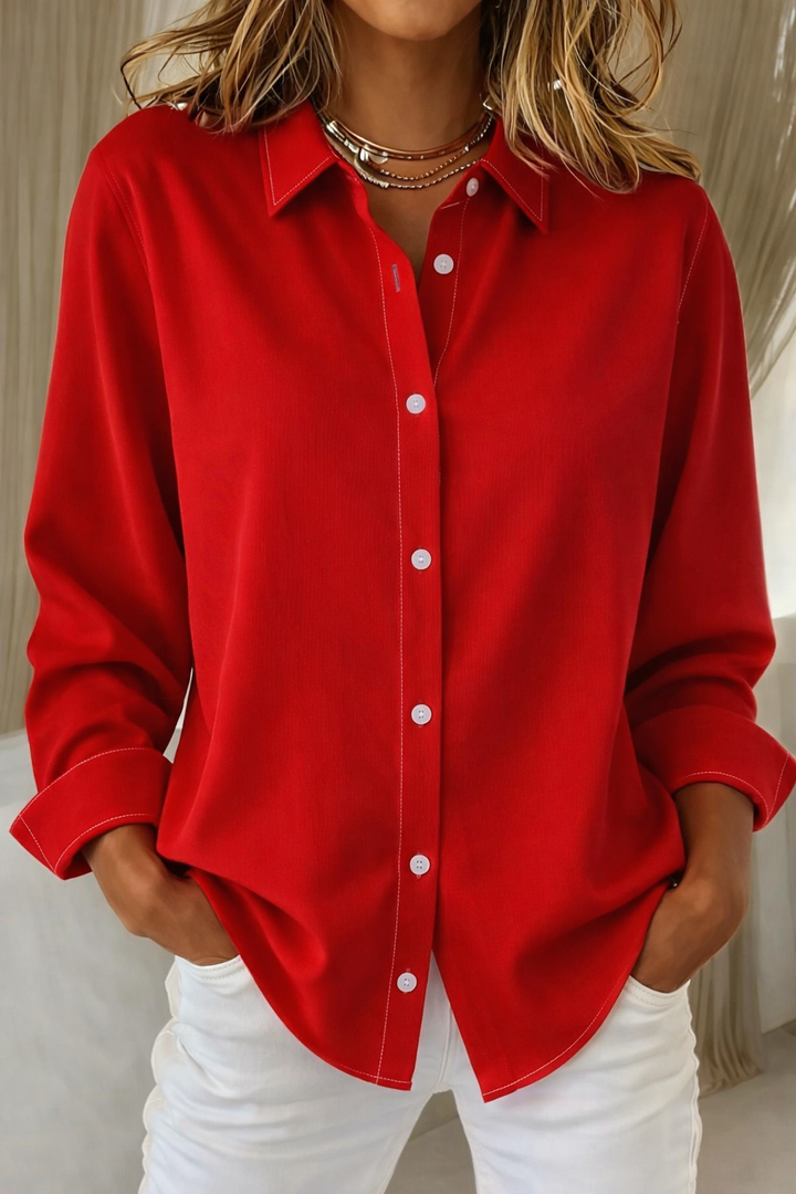 Female model wearing an elegant blouse with a soft drape on a plain background.