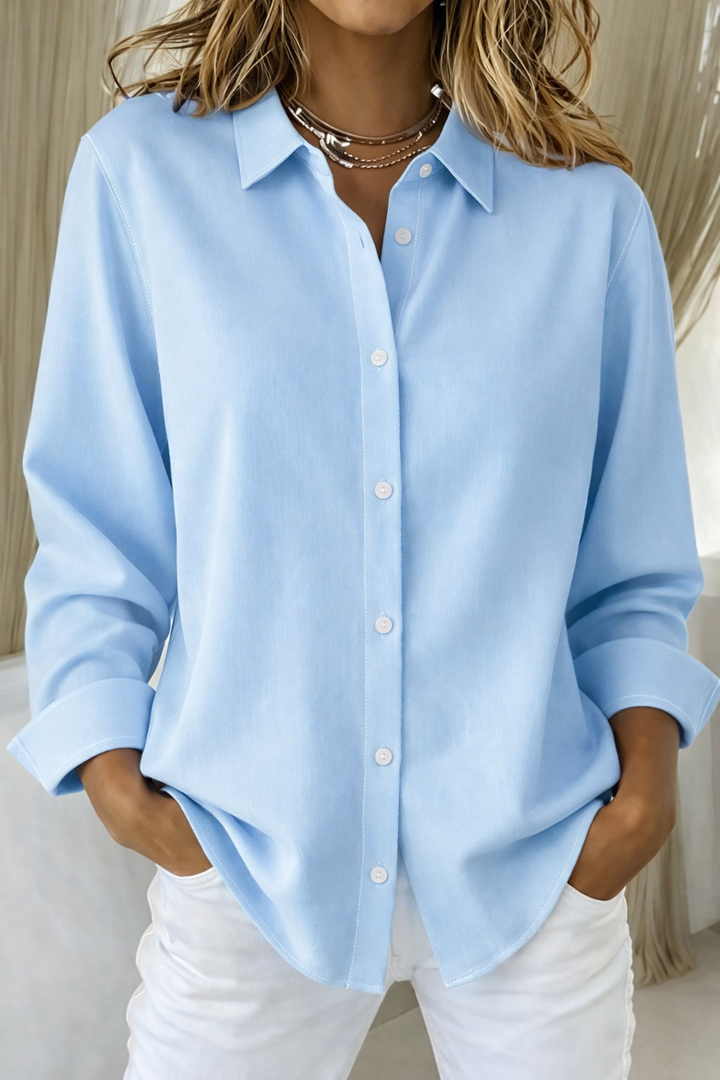 Model showcasing a timeless blouse with a graceful flowing design on a plain background.