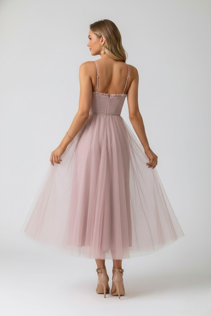 Female model wearing elegant party dress on plain gray background, back view