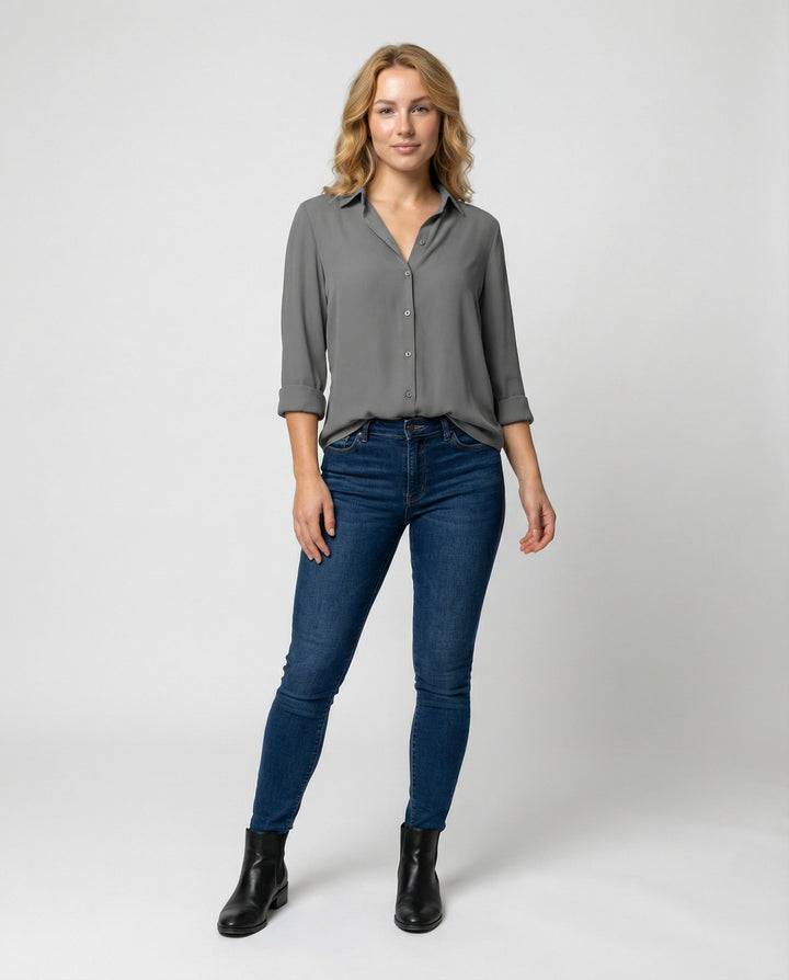 Woman showcasing a button-front blouse with a relaxed fit against a plain background.
